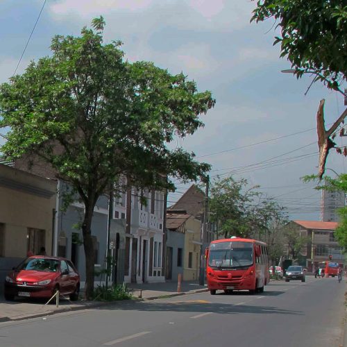 calle de ciudad con bus y con auto estacionado en la vereda